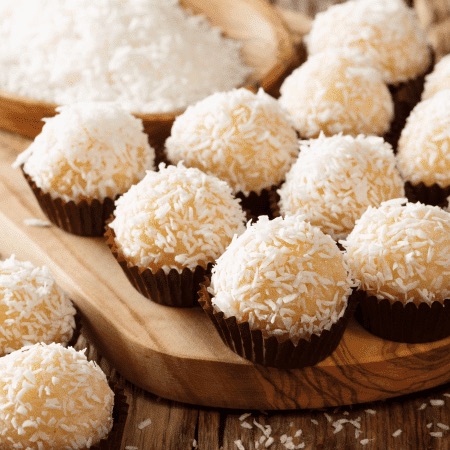 Brigadeiros de coco padronizados sobre tábua de madeira